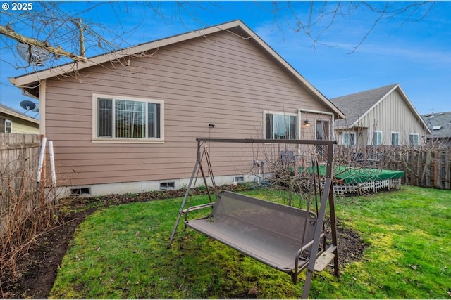 back of property with crawl space, fence, and a lawn