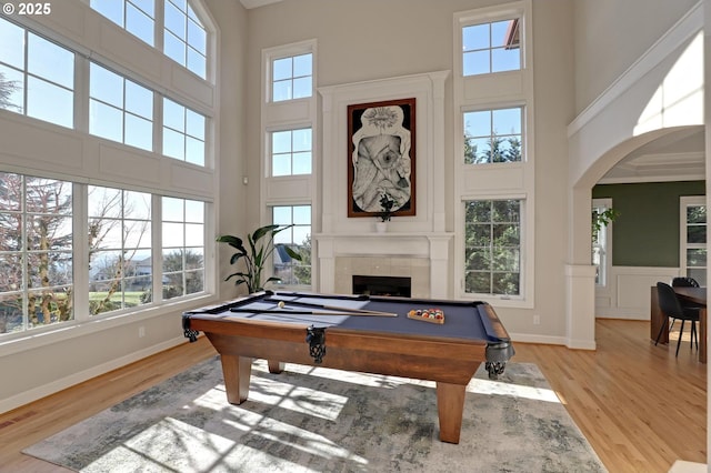 rec room with light hardwood / wood-style flooring, pool table, a towering ceiling, and a tile fireplace