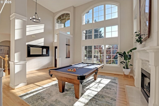 game room with light wood-type flooring, a high ceiling, a tile fireplace, and billiards