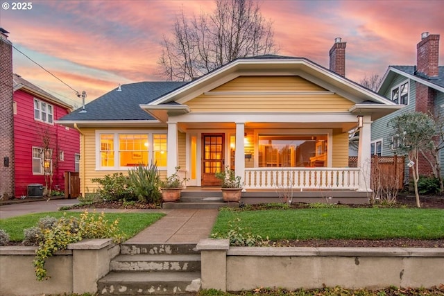 view of front of property with a yard, covered porch, and central AC