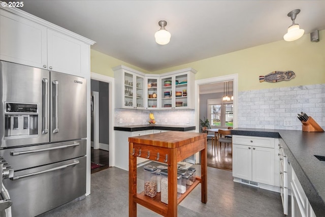 kitchen with backsplash, dark countertops, white cabinetry, glass insert cabinets, and high end refrigerator