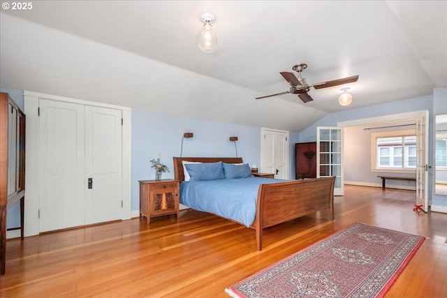 bedroom featuring light wood-type flooring, baseboards, ceiling fan, and vaulted ceiling