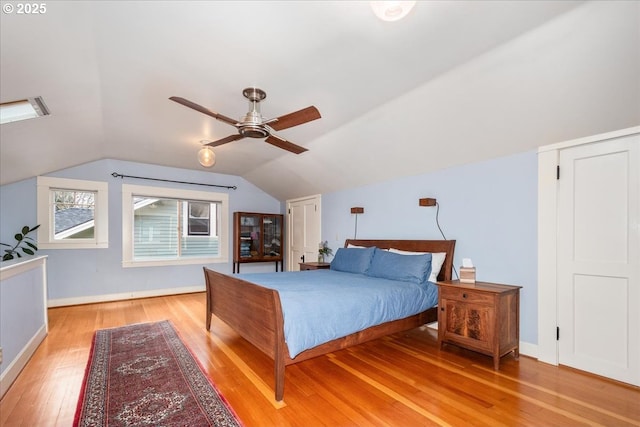 bedroom featuring baseboards, light wood-style flooring, a ceiling fan, and vaulted ceiling