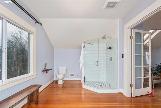 bathroom featuring visible vents, a stall shower, lofted ceiling, and wood finished floors