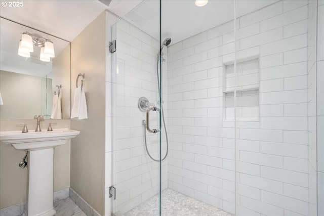 full bath featuring a sink, baseboards, and a tile shower