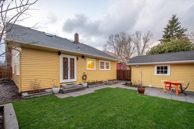 rear view of property with a lawn, a patio, fence, french doors, and a chimney