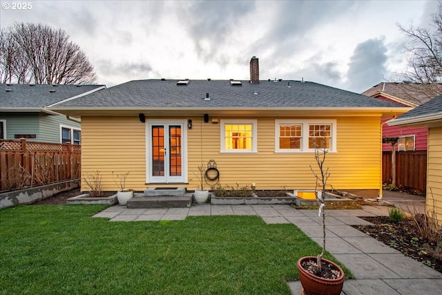 back of property with a lawn, a patio, a chimney, and a fenced backyard