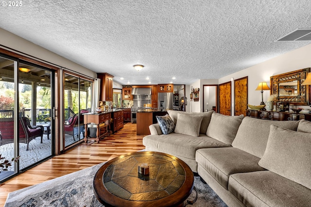 living room featuring light wood-type flooring, a textured ceiling, and recessed lighting