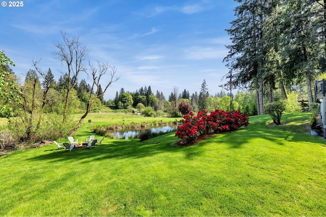 view of green lawn featuring an outdoor fire pit and a water view
