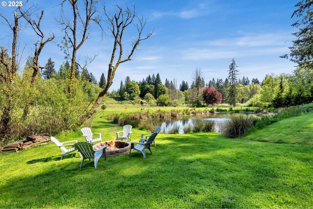 view of grassy yard featuring a fire pit and a water view