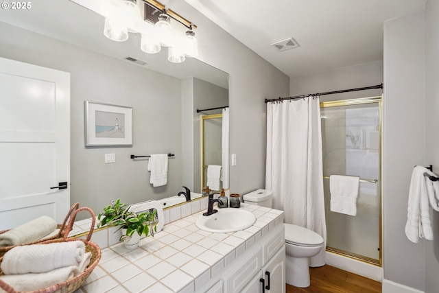 bathroom featuring a shower stall, toilet, visible vents, and wood finished floors