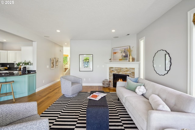 living area featuring baseboards, a stone fireplace, recessed lighting, and wood finished floors