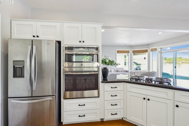 kitchen featuring a water view, stainless steel appliances, white cabinetry, and recessed lighting