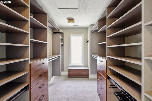 walk in closet featuring light carpet and attic access