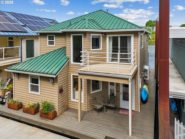 back of house featuring metal roof, a wooden deck, and a standing seam roof