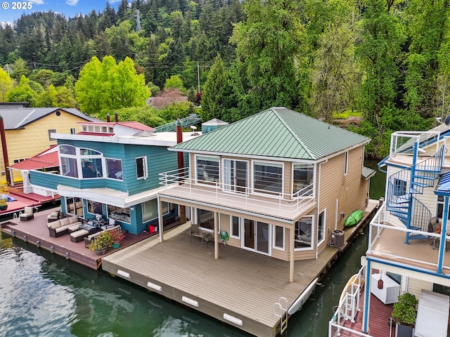 rear view of house featuring metal roof, a view of trees, and a deck with water view