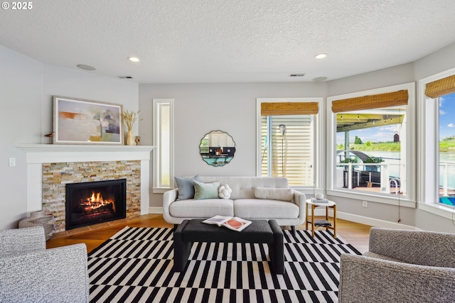 living area with a textured ceiling, recessed lighting, visible vents, and wood finished floors