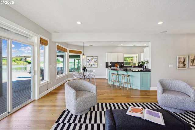 living area featuring recessed lighting, baseboards, and light wood-style floors