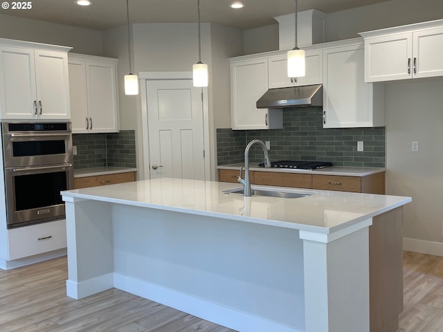 7863 SW Thornbridge Ter Unit 11, Beaverton, OR 97007 - kitchen featuring under cabinet range hood, stainless steel double oven, a sink, light wood-style floors, and baseboards