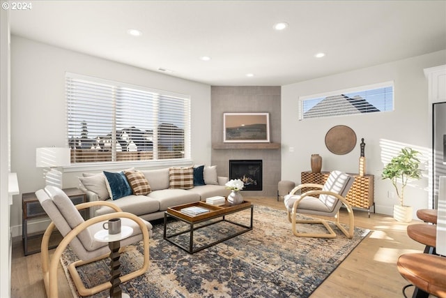 living room with a tiled fireplace and light wood-type flooring