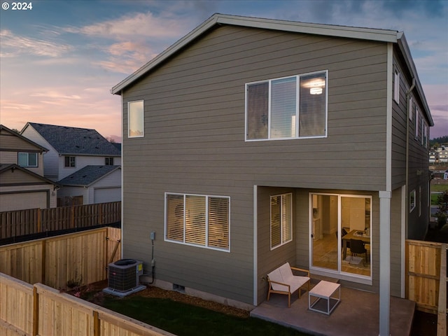 back house at dusk featuring central AC unit and a patio