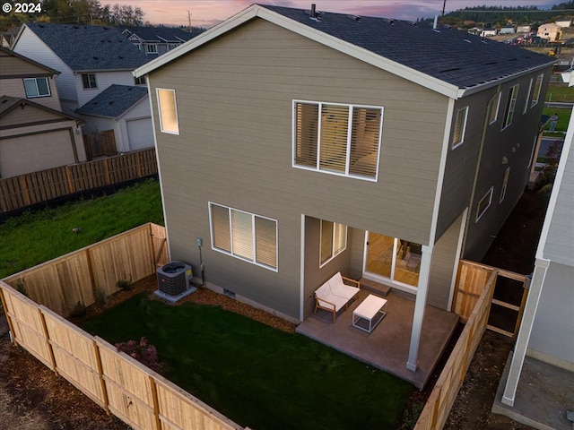 back house at dusk with cooling unit, a yard, and a patio area