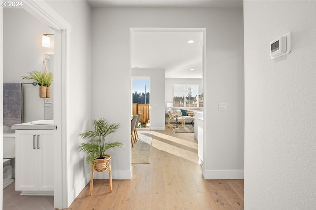 corridor featuring light wood-type flooring and baseboards