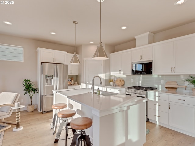 kitchen featuring a sink, white cabinetry, light wood-style floors, appliances with stainless steel finishes, and tasteful backsplash