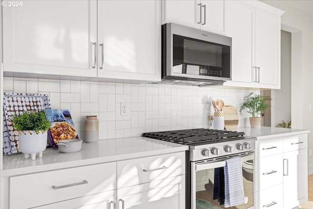 kitchen with backsplash, stainless steel appliances, and white cabinets