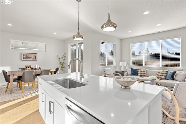 kitchen featuring sink, white cabinetry, decorative light fixtures, a center island with sink, and stainless steel dishwasher