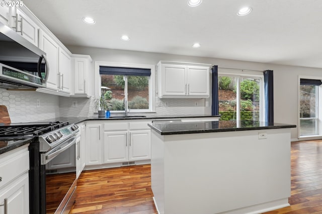 kitchen with white cabinets, stainless steel appliances, light wood-type flooring, and a center island