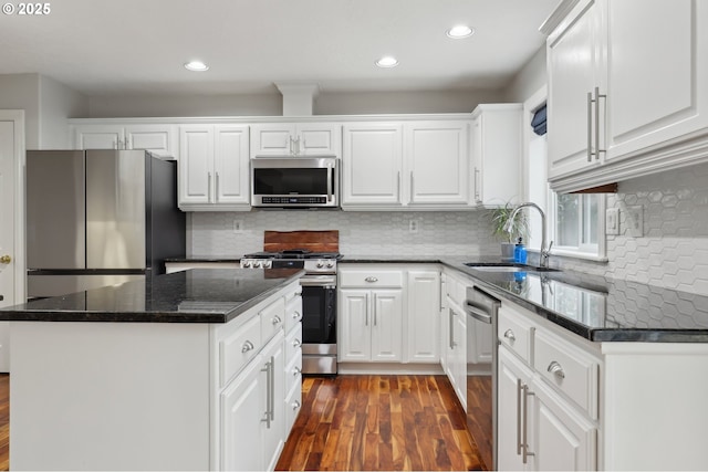 kitchen with stainless steel appliances, dark wood-type flooring, a kitchen island, white cabinets, and sink