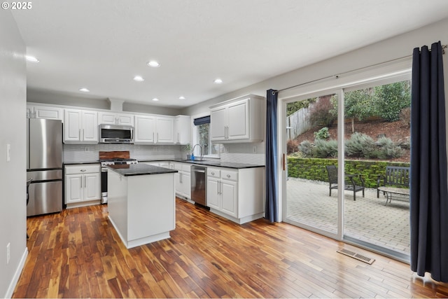 16374 SE Orchard View Ln, Damascus, OR 97089 - kitchen featuring stainless steel appliances, a sink, dark wood finished floors, dark countertops, and a kitchen island