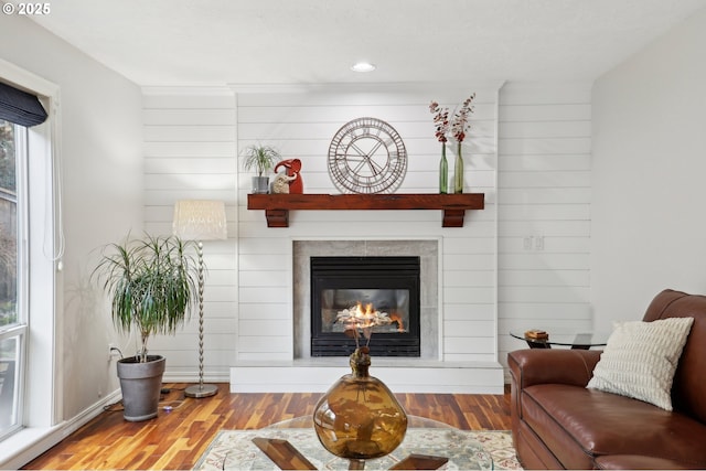 living room featuring a tiled fireplace and wood-type flooring