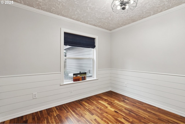 spare room featuring a textured ceiling, ornamental molding, and wood-type flooring