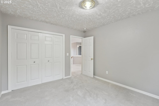 unfurnished bedroom featuring a textured ceiling, a closet, and light carpet