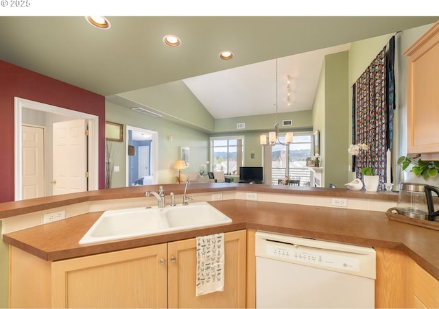 kitchen with light brown cabinets, white dishwasher, a sink, open floor plan, and a chandelier