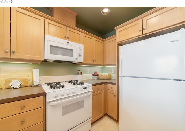 kitchen featuring white appliances, dark countertops, and light brown cabinets