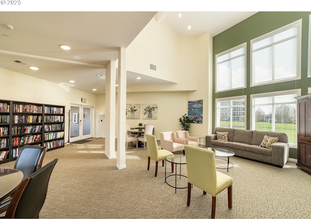 living area with recessed lighting, visible vents, light colored carpet, and a high ceiling