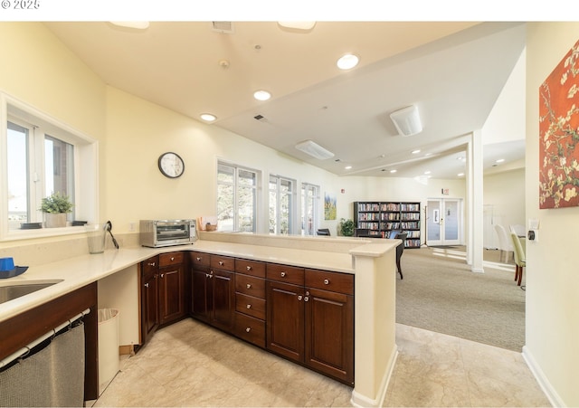 kitchen featuring a peninsula, a toaster, recessed lighting, light countertops, and light colored carpet