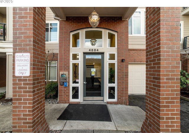 view of exterior entry featuring brick siding and a garage