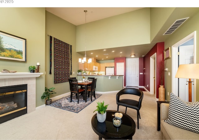 living room featuring baseboards, visible vents, light colored carpet, a towering ceiling, and an inviting chandelier