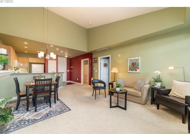 dining area featuring visible vents, baseboards, light carpet, an inviting chandelier, and a towering ceiling