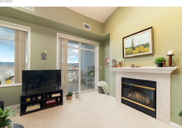 carpeted living area featuring a tiled fireplace and visible vents