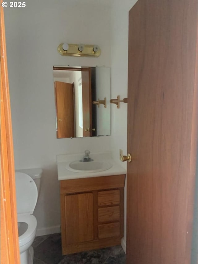 bathroom featuring baseboards, vanity, and toilet
