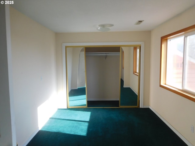 unfurnished bedroom featuring dark carpet and a closet