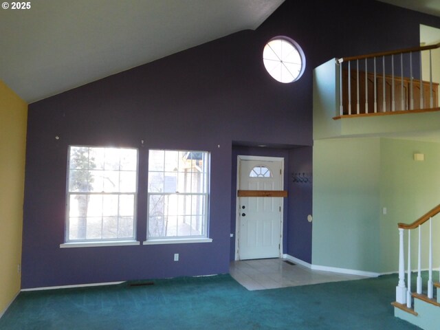 carpeted entryway with a wealth of natural light and high vaulted ceiling