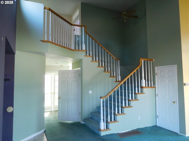 stairway featuring ceiling fan, carpet flooring, and a high ceiling