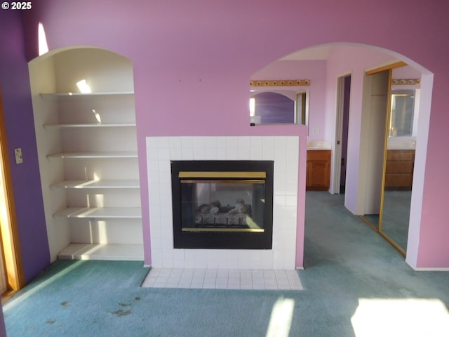 unfurnished living room with a tile fireplace, carpet, and built in features