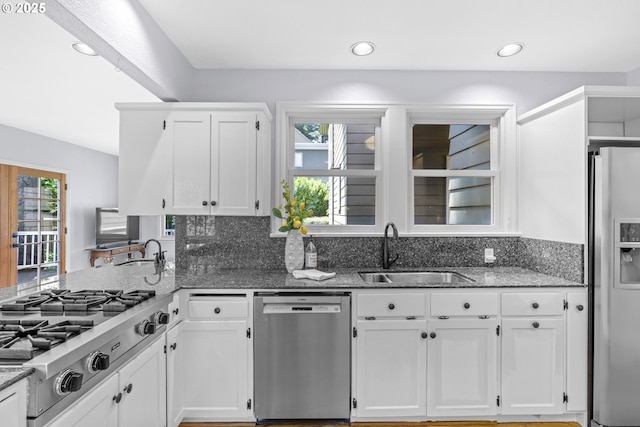 5707 SW Menefee Dr, Portland, OR 97239 - kitchen featuring stainless steel appliances, white cabinets, dark stone countertops, a peninsula, and recessed lighting
